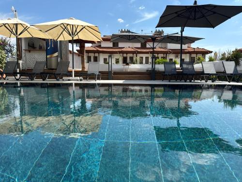 a swimming pool with chairs and umbrellas in front of a house at Tomsan Suites & Villas Akyaka in Akyaka