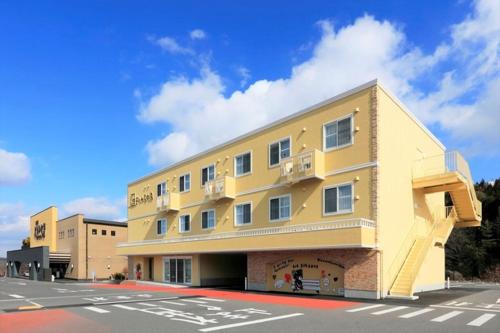 ein großes gelbes Gebäude an der Straßenseite in der Unterkunft Yorimichi no Yado - Vacation STAY 37453v in Toki