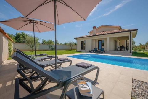 a patio with two chairs and umbrellas next to a pool at Ferienhaus Evida in Poreč