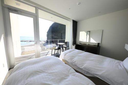 Beach Terrace Kushimoto - Vacation STAY 37415v في Wabuka: سريرين في غرفة نوم مطلة على المحيط