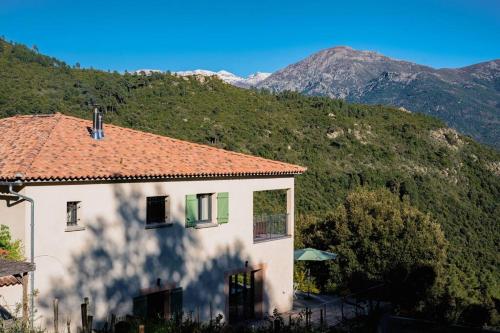 a white house with a red roof and a mountain at Appartement T3 bas de Villa in Vero