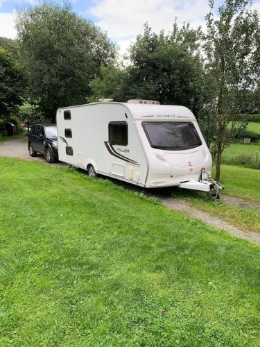 a white caravan parked next to a grass field at Family time in the Welsh hills! in Llanfyllin