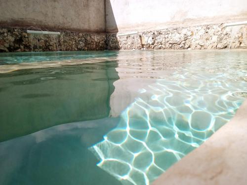 a pool of water next to a stone wall at Hotel y Museo Aldea Maya Toktli Orígenes - Suite Casa Maya Del Jabín - Alberca, Wifi Starlink, Tour Museo in Izamal