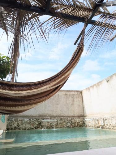 a hammock hanging over a swimming pool at Hotel y Museo Aldea Maya Toktli Orígenes - Suite Casa Maya Del Jabín - Alberca, Wifi Starlink, Tour Museo in Izamal