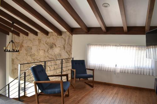 Habitación con 2 sillas azules y ventana en Loft Montenegro en Aguascalientes
