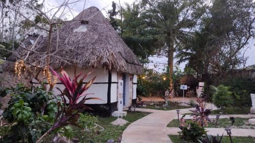a small hut with a thatched roof in a garden at Hotel y Museo Aldea Maya Toktli Orígenes - Casa Maya Toh - Alberca, Wifi Starlink, Tour Museo in Izamal