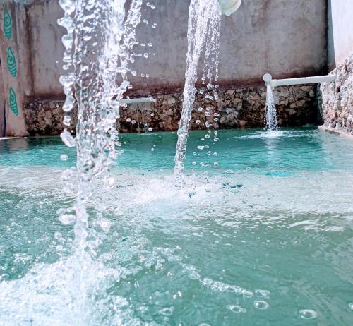 a water fountain in a pool of water at Hotel y Museo Aldea Maya Toktli Orígenes - Casa Maya Toh - Alberca, Wifi Starlink, Tour Museo in Izamal