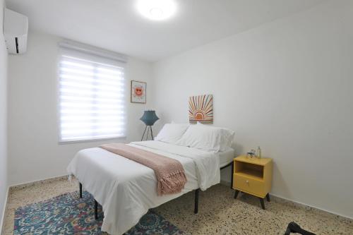 a white bedroom with a bed and a window at Casa Lula Beach Retreat - Dog friendly, Fenced backyard in Arecibo