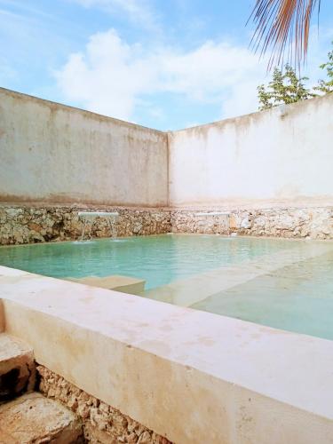 a swimming pool in a stone wall with blue water at Hotel y Museo Aldea Maya Toktli Orígenes - Casa Maya Melipona - Alberca, Wifi Starlink, Tour Museo in Izamal