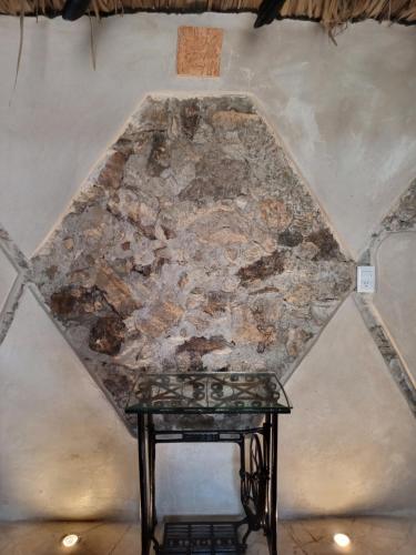 a glass table in front of a stone wall at Hotel y Museo Aldea Maya Toktli Orígenes - Suite Casa Maya 3 Culturas - Alberca, Wifi Starlink, Tour Museo in Izamal