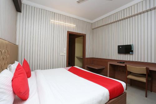 OYO Hotel K-town في Gharaunda: غرفة نوم بسرير ومكتب وتلفزيون