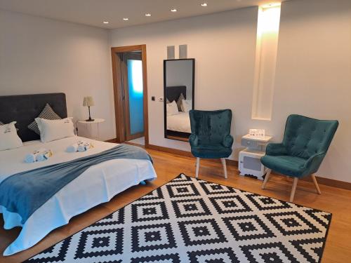 a bedroom with a bed and two chairs and a mirror at Quinta Salinas - Puro Prazer in Aveiro