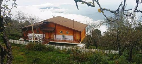 a large wooden house with a porch in a field at Praveen Woodhouse and Homestay Kodaikanal Vattakanal in Kodaikānāl