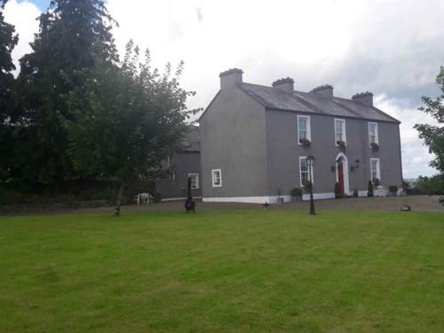 a large gray house with a large grass yard at Bealkelly Country House in Killaloe
