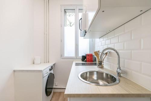 een witte keuken met een wastafel en een raam bij Appartement 2 personnes Neuf RDC in Gennevilliers