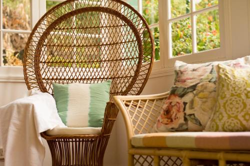 uma cadeira de vime com uma almofada ao lado de uma cadeira com uma janela em Casa Da Piedade em São Vicente
