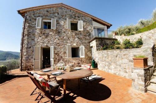 een stenen huis met een tafel en stoelen op een patio bij Ferienhaus mit Privatpool für 7 Personen ca 200 qm in Capannori, Toskana Provinz Lucca in Capannori