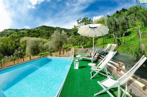 a swimming pool with two chairs and an umbrella at Ferienwohnung für 4 Personen ca 55 qm in Palmata, Toskana Provinz Lucca in Ciciana