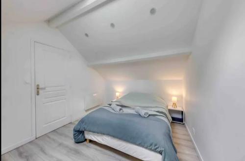 ein Schlafzimmer mit einem Bett in einem weißen Zimmer in der Unterkunft Maison avec jardin clos et privatif proche de Disneyland et parc des félins in Saint-Augustin