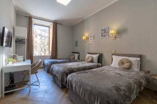 una camera d'albergo con due letti, una scrivania e una finestra di ESQUILINO HARMONY GUESTHOUSE - close to COLOSSEUM a Roma