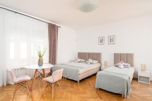 a bedroom with two beds and a table and chairs at Willa Zacisze - Pokoje Gościnne in Wrocław