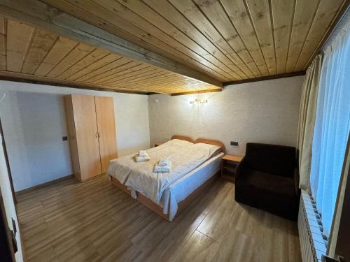 a small bedroom with a bed and a chair at Villa Raiski kyt in Dospat