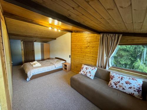 a bedroom with a bed and a couch in a room at Villa Raiski kyt in Dospat