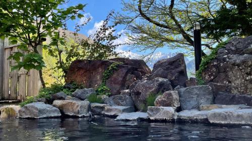 einen Pool mit Felsen und Bäumen in der Unterkunft Nakanoyu Onsen Ryokan - Vacation STAY 18804v in Matsumoto