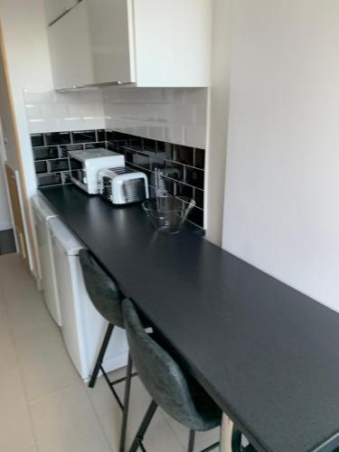 a black counter in a kitchen with two chairs at APPARTMENT IN LONDON in London