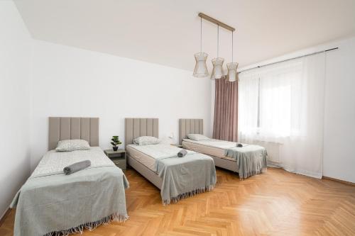two beds in a room with white walls and wooden floors at Willa Zacisze - Pokoje Gościnne in Wrocław