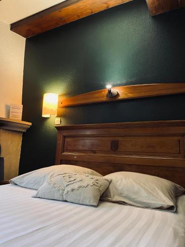 a bed with a wooden headboard and a green wall at Le Château du Landsberg in Barr