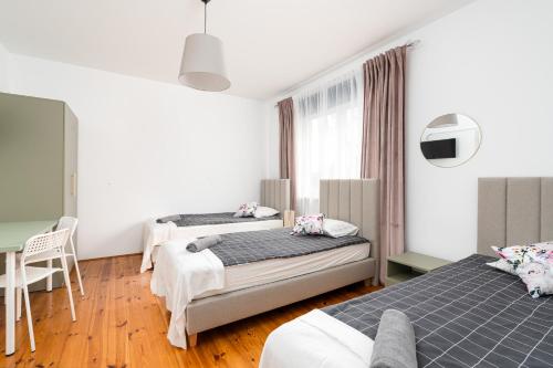 a bedroom with two beds and a tv at Willa Zacisze - Pokoje Gościnne in Wrocław