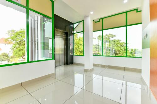 an empty lobby with windows and white tile floors at Flagship Green Line Residency in Nedumbassery