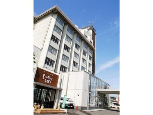 un edificio blanco alto con un coche aparcado delante de él en Tottori Onsen Shiitake Kaikan taisuikaku - Vacation STAY 21939v, en Tottori