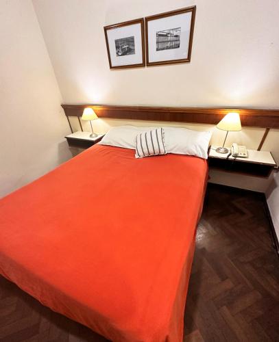 a bedroom with a large orange bed with two lamps at Castelar Hotel Santa Fe in Santa Fe