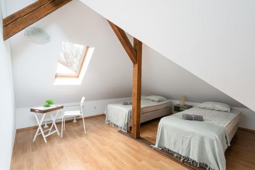 a attic bedroom with two beds and a table at Willa Zacisze - Pokoje Gościnne in Wrocław