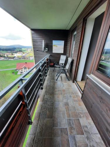 ハイトミューレにあるGroße Ferienwohnung in Ludwigsreut mit Eigenem Balkonのバルコニー(椅子付)、大きな窓が備わります。
