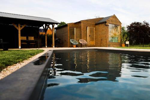 a swimming pool in front of a wooden house at ChillHouse by Kis Veréb in Békésszentandrás