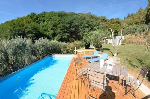 una piscina con una terraza de madera y sillas junto a ella en Ferienhaus mit Privatpool für 4 Personen ca 50 qm in Loppeglia, Toskana Provinz Lucca, en Loppeglia