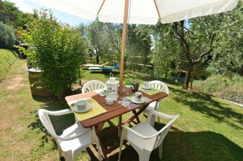a wooden table with white chairs and an umbrella at Ferienhaus mit Privatpool für 4 Personen ca 50 qm in Loppeglia, Toskana Provinz Lucca in Loppeglia