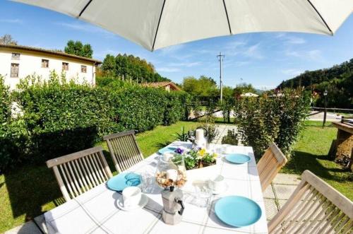 Monsagrati的住宿－Ferienwohnung für 4 Personen ca 50 qm in Monsagrati, Toskana Provinz Lucca，一张带椅子的白色桌子和一把雨伞