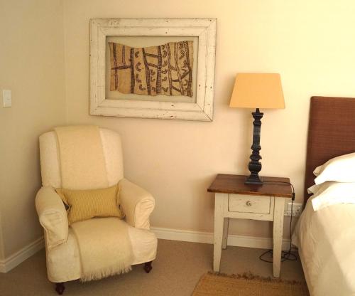 a bedroom with a chair and a lamp next to a bed at Logis König in Swakopmund