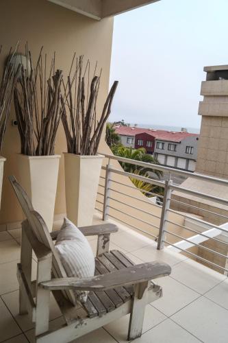 a wooden chair sitting on a balcony with plants at Logis König in Swakopmund