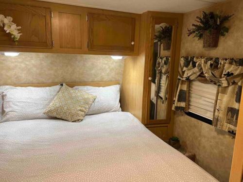 a bedroom with a bed with white sheets and cabinets at WARM AND COZY RV 3 in Miami