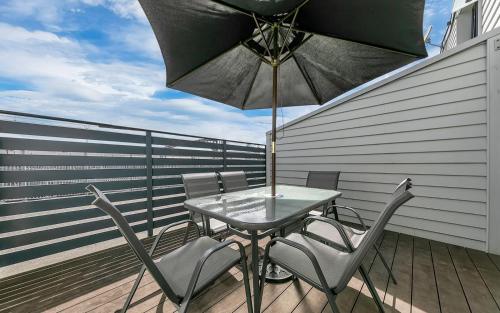 una mesa y sillas en un balcón con sombrilla en Balcony and Parking 3BR Gem Near Arena by Zodiak Stays, en Auckland