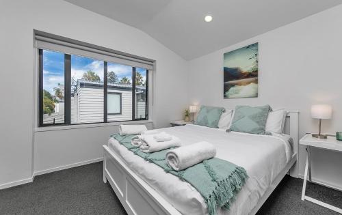 Un dormitorio blanco con una cama grande y una ventana. en Balcony and Parking 3BR Gem Near Arena by Zodiak Stays, en Auckland