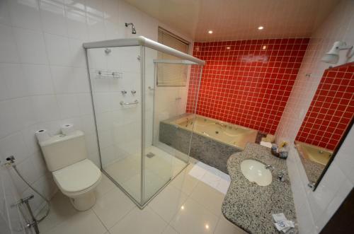 a bathroom with a toilet and a shower and red tiles at Rede Andrade GV Center Hotel in Governador Valadares