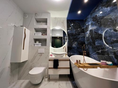 La salle de bains est pourvue de toilettes blanches et d'un lavabo. dans l'établissement Apartament Ultramaryna - Reda Aquapark Lipova Park, à Reda