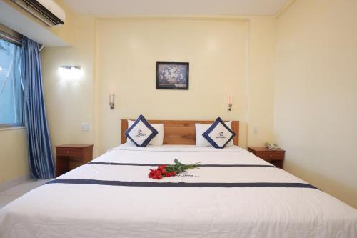 a bedroom with a large white bed with flowers on it at Khách Sạn Hạnh Long in Ho Chi Minh City