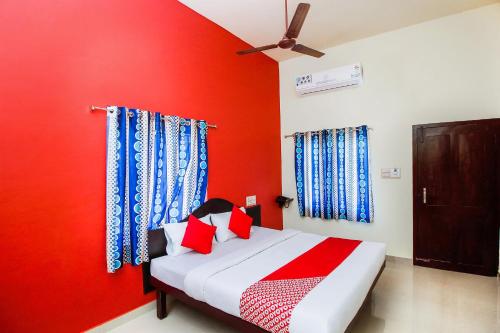 a bedroom with a red wall with a bed and a ceiling at Hotel Aljemin in Kanyakumari